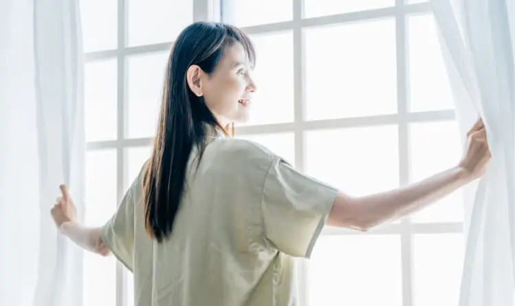 カーテンを開けている女性